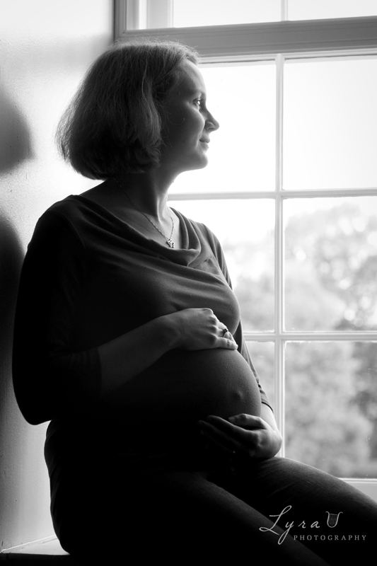 Black and white expectant mom silhouetted at window