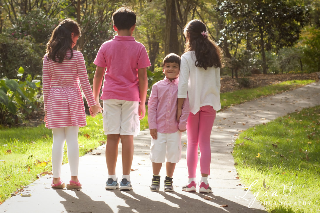 Four children in pink and white on a sidewalk